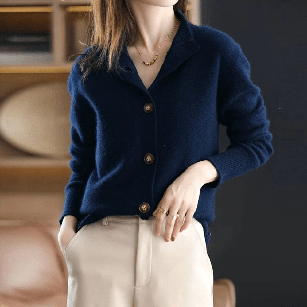 Person wearing a navy blue cardigan with beige pants in an indoor setting